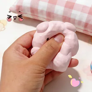 Soft pink pig-shaped silicone squishy toy for stress relief being squeezed by hand.