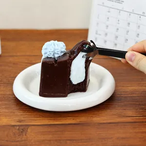 Close-up of chocolate cake squishy being pinched with tweezers on a white plate