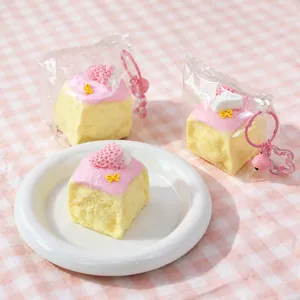 Dettaglio di uno squishy a forma di torta alle fragole rosa con portachiavi e campanello
