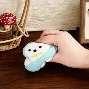 Χέρι που πιέζει ένα λευκό αρκουδάκι squishy με μπλε σαλοπέτα για την υφή του