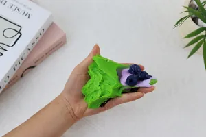 Close-up of green blueberry cake silicone squishy toy held in hand to show soft texture
