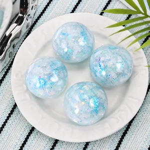 Close-up of four glittery blue handmade silicone squeeze balls on a white plate