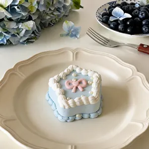 Close-up detail of a blue star-shaped cake squishy toy with pink bow and cream trim on a plate
