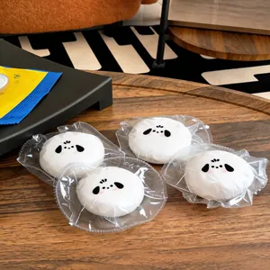 Close-up of four puppy-shaped silicone squishy toys individually wrapped on a wooden surface