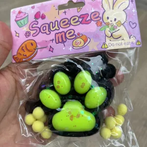 Nahaufnahme eines schwarzen Katzenpfoten-Squishys mit neongrünen Pads und Glitzerakzenten