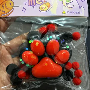 Dettaglio di un grande squishy a forma di zampa di gatto rosso e nero con paillettes