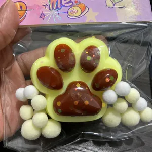 Primo piano di uno squishy a zampa di gatto giallo con paillette nella confezione