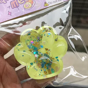 Detail view of a yellow glittery starry cat paw squeeze toy in clear plastic wrap