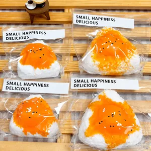 Detailed macro view of four egg yolk onigiri squishy toys in individual clear packaging