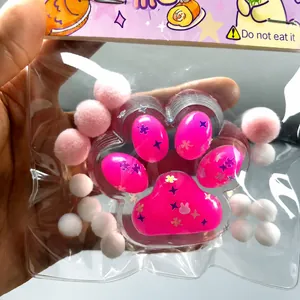 Close-up of a pink cat paw squishy stress relief toy with cute decorative pom-poms