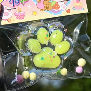 Detail view of a cute lime green paw squishy toy with colorful glitter and sequins inside packaging.