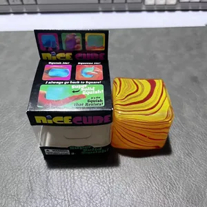 NeeDoh Nice Cube Stressabbau-Spielzeug mit rot-gelbem Wirbelmuster und Originalverpackung.
