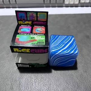 Blau marmoriertes Nice Cube Squishy-Spielzeug neben seiner bunten Verkaufsverpackung.