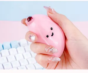 Close-up of hand squeezing a cute pink banana squishy toy for effective stress relief.