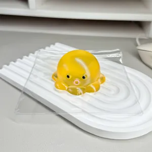 Close-up detail of a translucent yellow octopus stress relief toy resting on a white wavy tray
