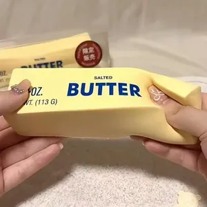 Close-up of hands squeezing a realistic salted butter stick slow rebound squishy stress toy