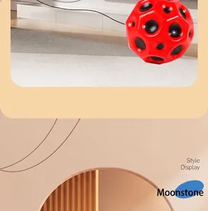 Detailed view of a bright red moon ball with distinctive black crater-like holes