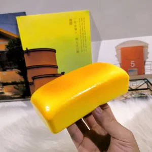 Yellow bar-shaped simulation bread squishy toy held in hand for stress relief