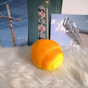 Detailed close-up of jumbo orange-yellow slow-rising pig bun bread squishy toy on white fur