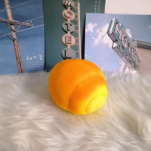 Detailed macro shot of a soft, slow-rising yellow bread squishy toy on a white rug.