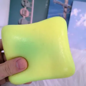 Detail view of a neon yellow cheese toast bread squishy toy being squeezed in hand.
