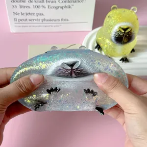 Close-up detail of a squishy capybara stress toy with glitter being squeezed by hands