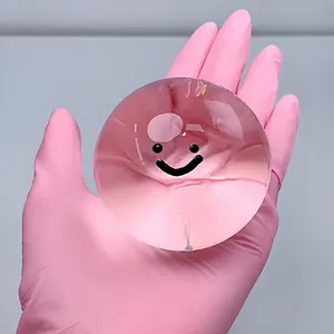 Giocattolo squishy a bolla di cristallo trasparente con faccina sorridente in guanto rosa.