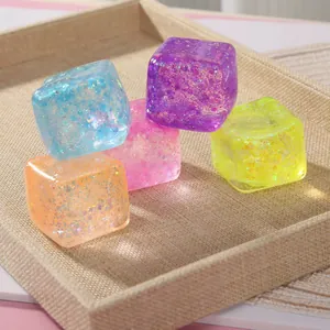 Colorful glitter squishy cubes for stress relief on a linen tray
