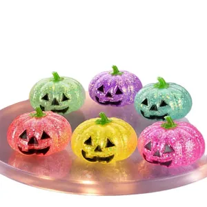 Close-up of six colorful glitter Halloween jack-o-lantern squishy toys on a purple plate