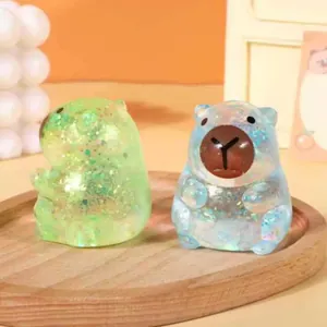 Detailansicht von zwei glitzernden, durchsichtigen Capybara-Antistress-Spielzeugen auf Holztablett