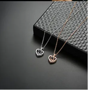 Detail of two heart projection necklaces in silver and rose gold on a black box