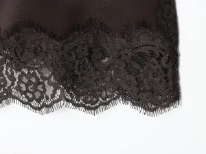 Detailed close-up showing the delicate black lace hem of a smooth satin camisole top