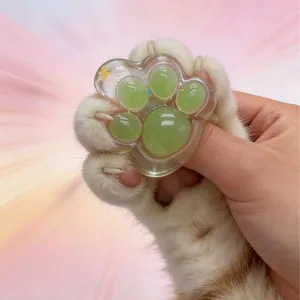 Close-up of a hand squeezing a transparent green cat paw squishy toy for stress relief.