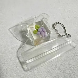 Close-up of clear squeeze toy pouch featuring a purple grape charm and metal ball chain.