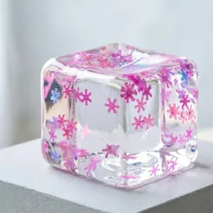 Translucent ice cube squishy stress toy with decorative pink snowflake glitter accents