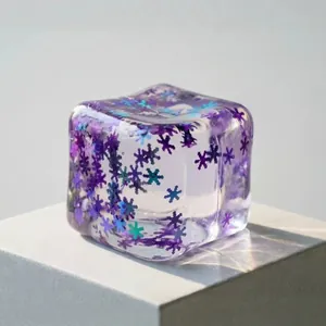 Translucent ice cube squishy stress toy with purple snowflake glitter inserts inside.