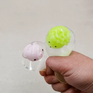 Primo piano di una mano che schiaccia palline antistress trasparenti con figure di animali
