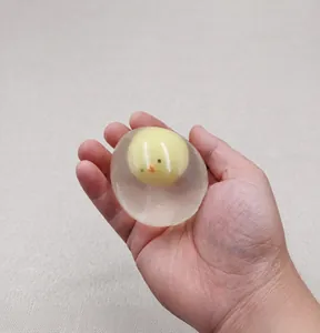 Dettaglio di una pallina antistress a forma di uovo con pulcino tenuta in mano.