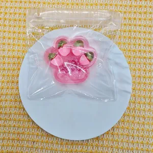 Close-up of pink cat paw squishy decompression toy with strawberry charms in clear packaging