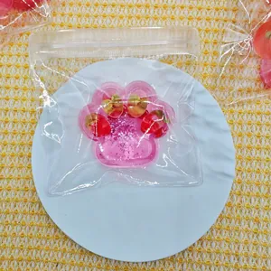 Detail shot of pink cat paw squeeze toy with glitter and strawberry inclusions in a bag.