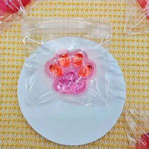 Close-up of a pink glitter strawberry cat paw squeeze toy inside transparent zip-lock packaging