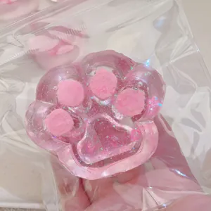Detailed view of a pink cat paw squishy toy featuring glitter inside a clear plastic bag