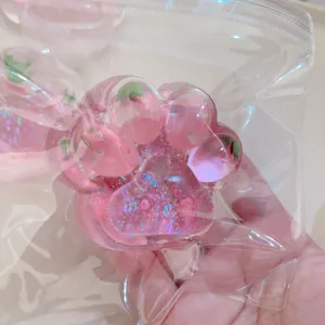 Close-up detail of a glittery pink strawberry cat paw squishy toy in a clear zip bag.