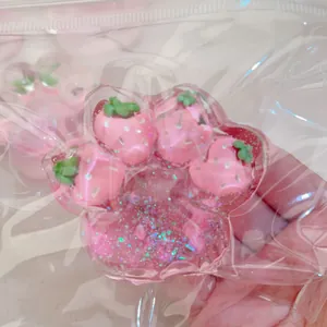 Close-up view of a pink strawberry cat paw squishy toy inside clear plastic bag