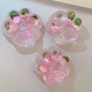 Detailed view of three translucent pink cat paw squishy toys with strawberry inserts