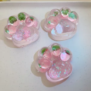 Detail of three pink translucent strawberry-themed cat paw squishy toys with glitter inside.