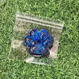 Blue glitter cat paw squeeze toy for stress relief on artificial grass background