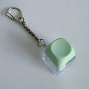 Detailed view of mechanical keyboard switch keychain with a mint green rounded keycap