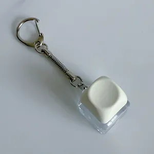 Macro detail of a mechanical keyboard switch keychain fidget toy with a white keycap.