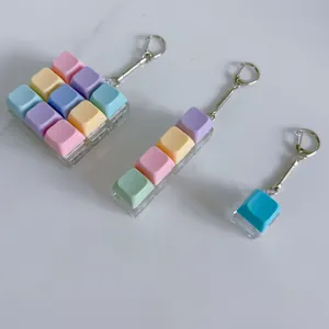 Detail view of macaron mechanical keyboard keycap fidget keychains in three size variations.
